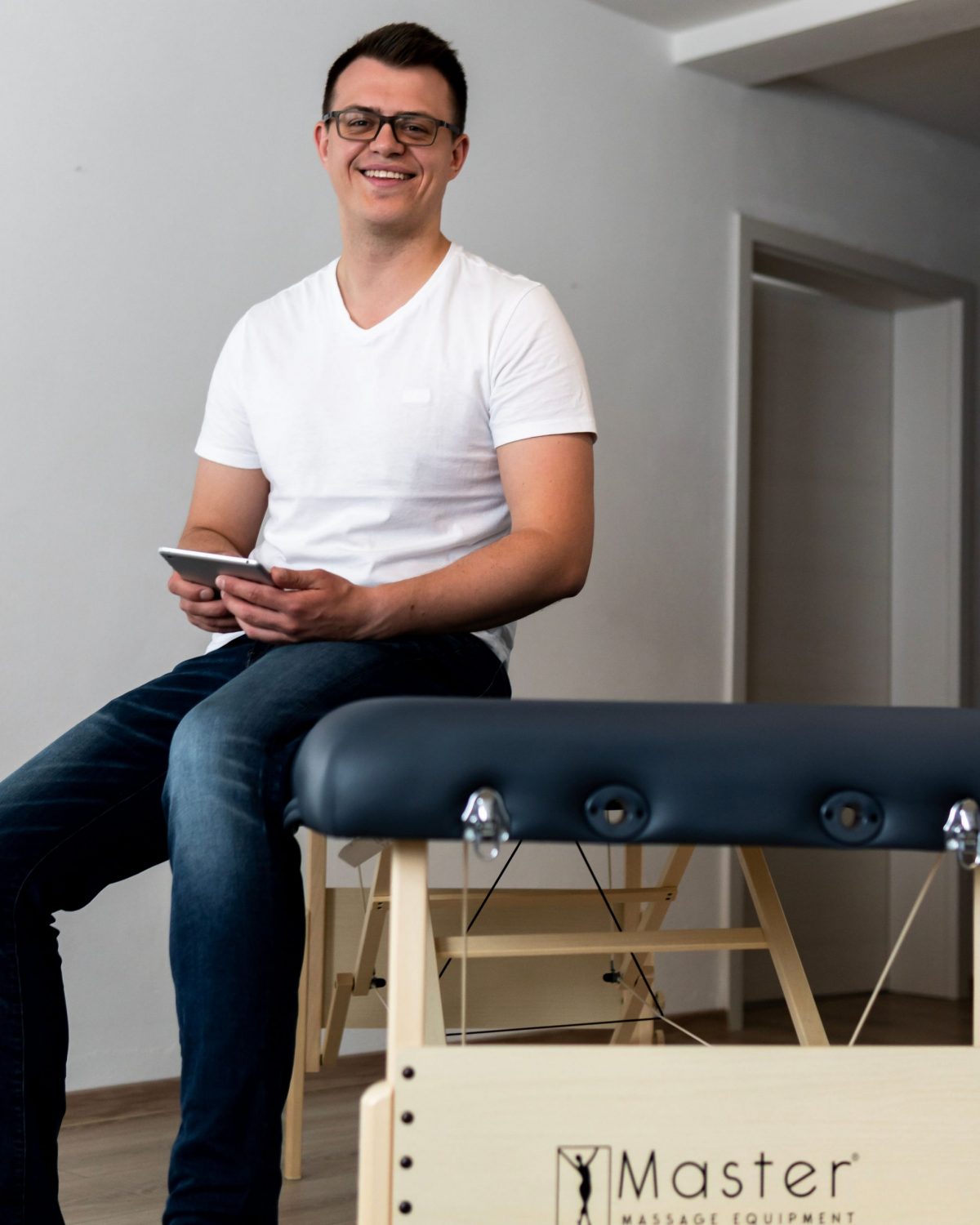 Alexander Steinborn sitzt auf einer mobilen Massageliege